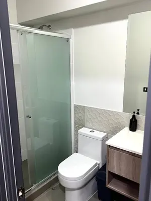 a bathroom with a toilet and a glass shower at Modern Apartment for 9 San Isidro in Lima