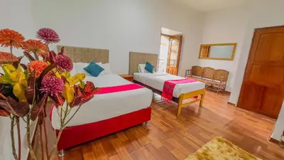 a hotel room with two beds and flowers in a room at Casona MICA'S HOUSE in Cusco