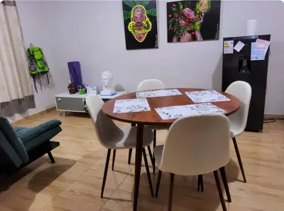 a dining room with a table and white chairs at Casa hogareña Pequeña in Ica