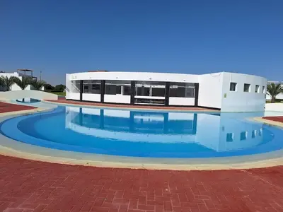 a building with a swimming pool in front of it at Paracas Exclusivo Departamento familiar in Pisco