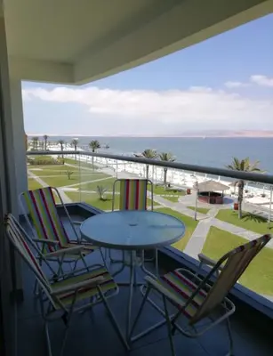 a balcony with a table and chairs and the ocean at Paracas Exclusivo Departamento familiar in Pisco