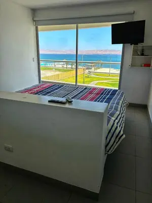 a bedroom with a bed with a view of the ocean at Paracas Exclusivo Departamento familiar in Pisco