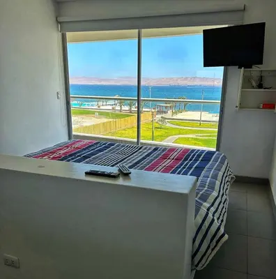 a bedroom with a bed with a view of the ocean at Paracas Exclusivo Departamento familiar in Pisco