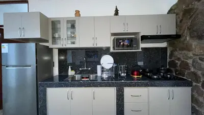 a kitchen with white cabinets and a black counter top at Casa Departamento en el Valle de Urubamba in Urubamba