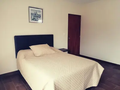 a bedroom with a bed with a white comforter at Casa Ribera Este in Cieneguilla