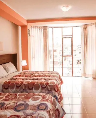 a hotel room with a bed and a large window at Hotel Bartol in Huancayo