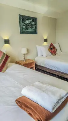 a bedroom with two beds and a picture of a motorcycle on the wall at Kayara Cusco Hotel in Cusco