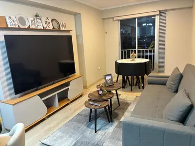 a living room with a large television and a table at Modern apartment overlooking Parque de las Aguas in Lima