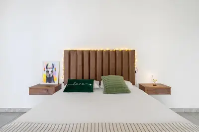 a white bed with two green pillows on it at Huaral House Piscina y Terraza in Huaral