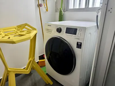 a washing machine in a room with a yellow stool at Departamento completo vista al mar,piscina,gimnasio,WIFI,Tvs in Lima