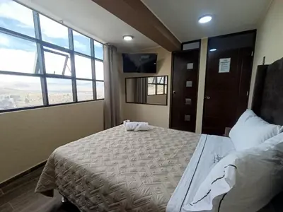 a bedroom with a large bed and a large window at Kapricho Wanka in Huancayo