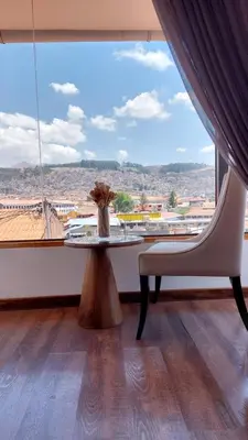 a table and a chair in a room with a large window at Casa Esmeralda by Katari in Cusco