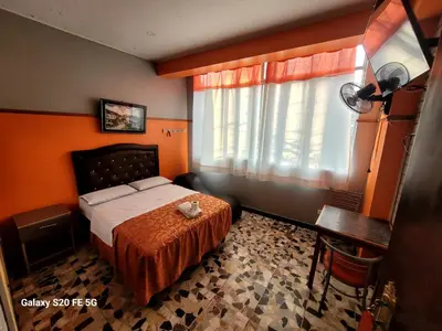 a bedroom with a bed and a desk and a window at Las Estrellas Hostal in Puente Piedra