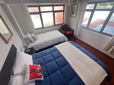 a bedroom with two beds and two windows at Legendary Rock Cusco Apartment in Cusco
