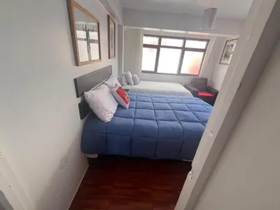 a bedroom with a bed with a blue blanket at Legendary Rock Cusco Apartment in Cusco
