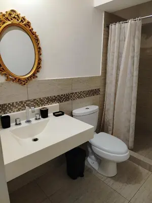 a bathroom with a sink and a toilet and a mirror at Departamento Executive 2BR Balcón Frente al Mall Santa Catalina in Lima