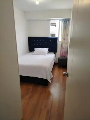 a small bedroom with a bed and a wooden floor at Departamento Executive 2BR Balcón Frente al Mall Santa Catalina in Lima