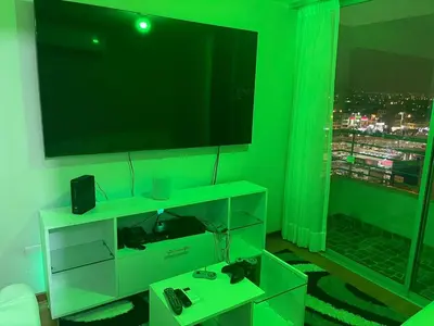 a living room with a green wall with a tv at New Apartment near the airport with parking in Lima