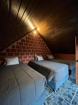 a room with two beds and a brick wall at AndeStay Hostel Chaullay in Colcapampa