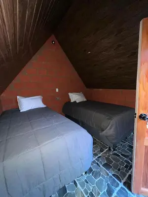 two beds in a room with a brick wall at AndeStay Hostel Chaullay in Colcapampa