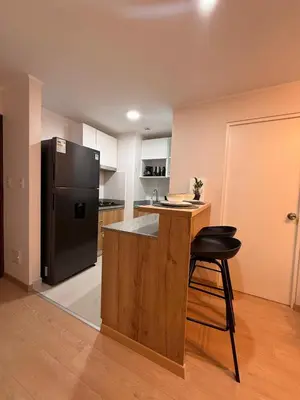 a kitchen with a black refrigerator and a table and a stool at Private cinema & comfort in cultural Barranco in Lima