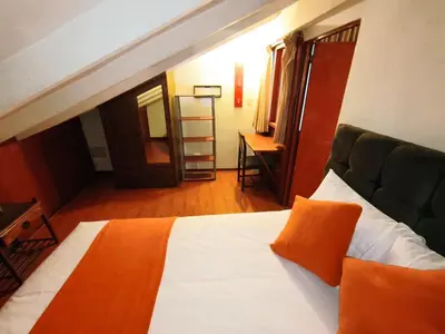 a bedroom with a bed with an orange pillow on it at Mayu House Inn V en el Centro Historico in Cusco