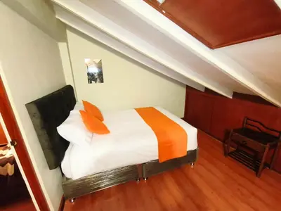 a bedroom with a bed with orange and white sheets at Mayu House Inn V en el Centro Historico in Cusco