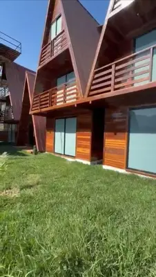 a house with a green lawn in front of it at Alpinas Natural Suites in Lunahuaná