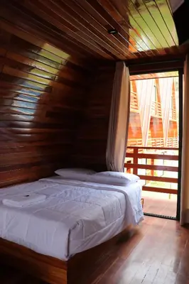 a bed in a room with a wooden ceiling at Alpinas Natural Suites in Lunahuaná