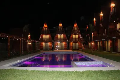 a swimming pool in front of a building at night at Alpinas Natural Suites in Lunahuaná