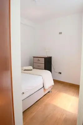 a small bedroom with a bed and a dresser at Apart Hotel Alojate Kaypi in Ayacucho