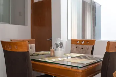 a dining room table with chairs and a glass table top at Apart Hotel Alojate Kaypi in Ayacucho