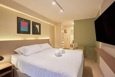 a bedroom with a white bed and a flat screen tv at Larco Prime Suites - Pool, Gym & Coworking in Lima