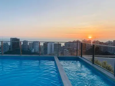a swimming pool on top of a building with the sunset at Loft en Barranco in Lima