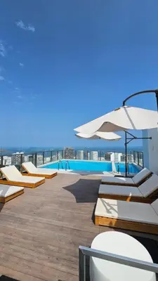 a deck with chairs and an umbrella and a pool at Loft en Barranco in Lima
