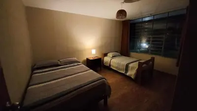 a bedroom with two beds and a window with a lamp at Casa de campo Yangas para 20 personas in Yangas
