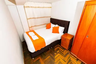a small bedroom with a bed with orange pillows at Mayu House Inn IV en el centro histórico in Cusco