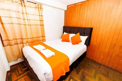 a bedroom with a bed with orange and white pillows at Mayu House Inn IV en el centro histórico in Cusco