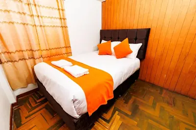 a bedroom with a bed with orange and white pillows at Mayu House Inn IV en el centro histórico in Cusco