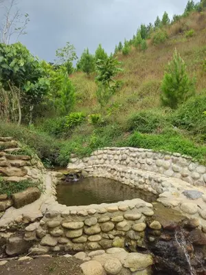 a rock wall around a pond on a hill at La Montaña Lodge - Oxapampa in Oxapampa