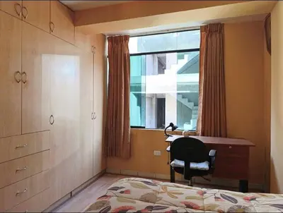 a bedroom with a desk and a chair and a window at Residencial Huancaro Apartament in Cusco