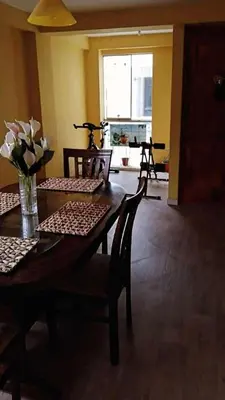 a dining room table with chairs and a vase of flowers at Residencial Huancaro Apartament in Cusco