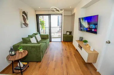 a living room with a green couch and a tv at BSR Brand New Apt Near Larcomar w/ Parking & Gym in Lima