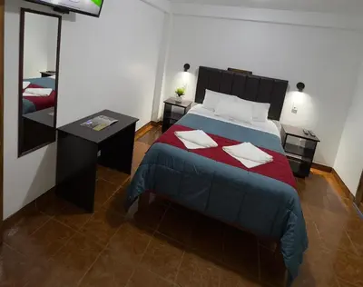 a bedroom with a bed with a red blanket and a mirror at Hospedaje San Francisco in Machu Picchu