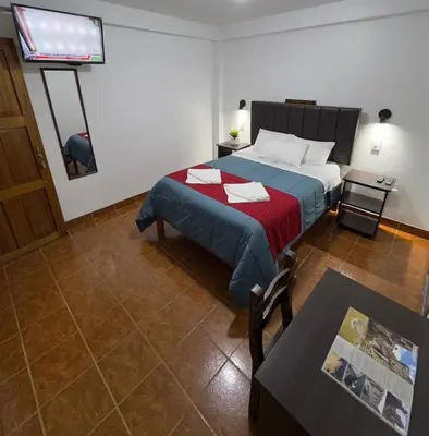 a bedroom with a bed with a tv on the wall at Hospedaje San Francisco in Machu Picchu