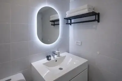 a white bathroom with a sink and a mirror at Modern Apartment with AC and Pool near Miraflores, Fast WiFi in Lima