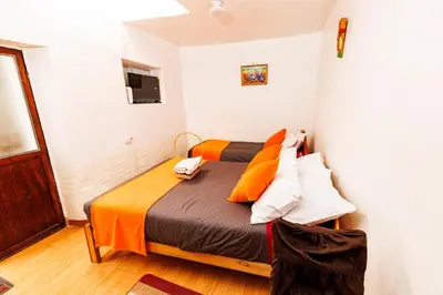 a bedroom with a bed with orange and brown pillows at Mayu House Inn I a minutos de la plaza in Cusco
