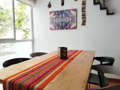 a wooden table with chairs and a rug on it at Coliving Barranco in Lima