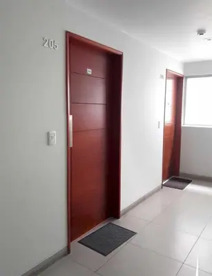 an empty hallway with a wooden door and a window at Coliving Barranco in Lima
