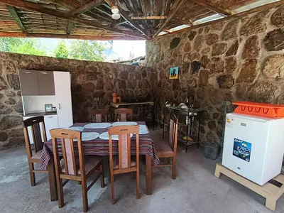 a table and chairs in a room with a stone wall at Hostal Ayllu con cochera in Urubamba